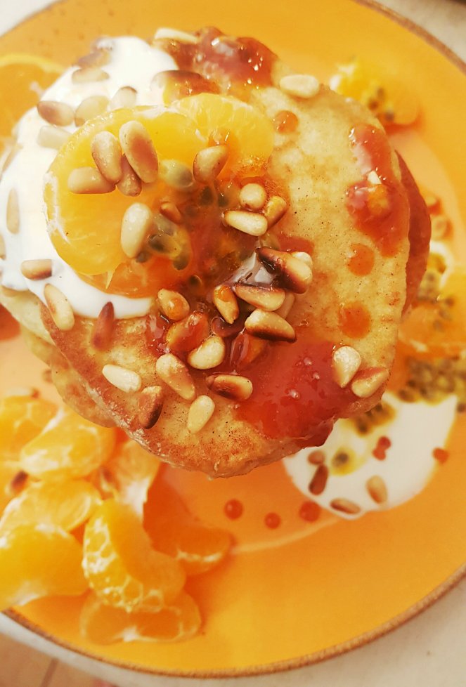 ein Stapel luftige Pancakes mit köstlichem Orangensirup und Pinienkernen